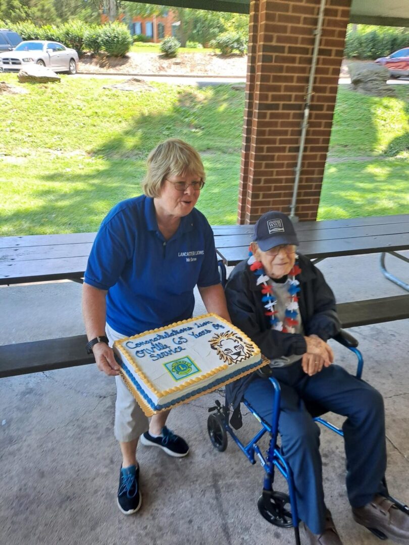 A man in a wheelchair and a woman presenting a cake