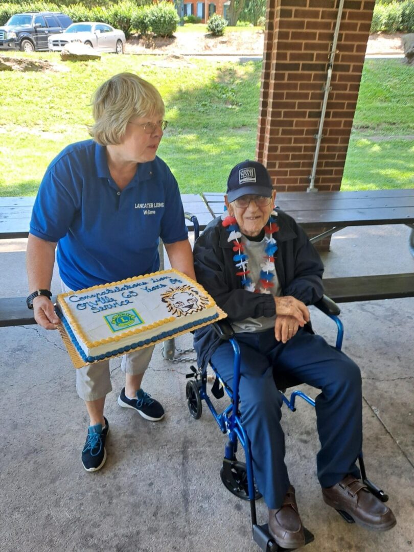 A man in a wheelchair and a woman presenting cake
