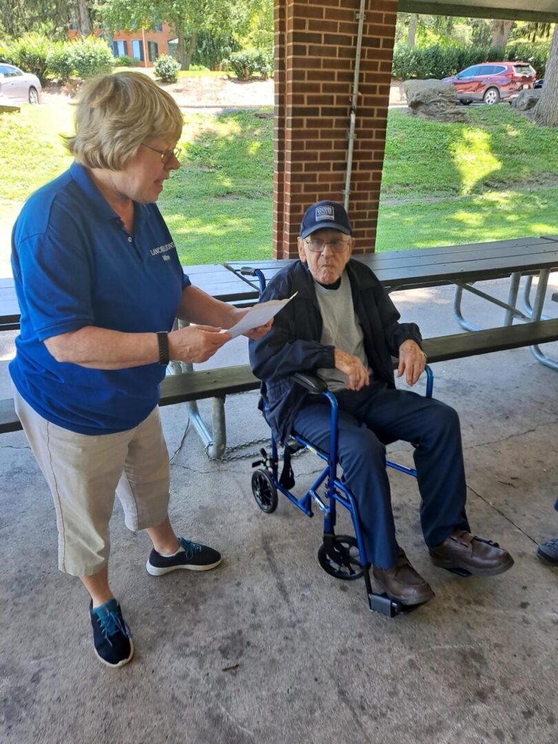 A man in a wheelchair and a woman standing with a paper