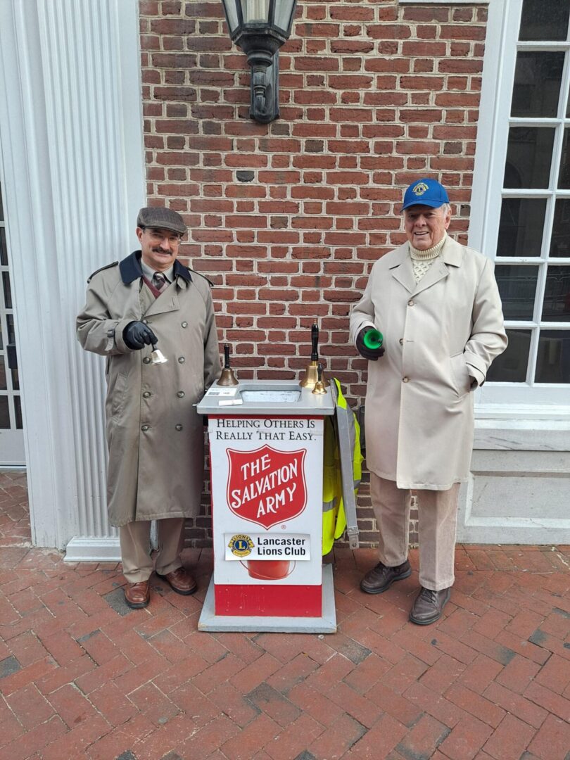 Two men standing beside the salvation army box