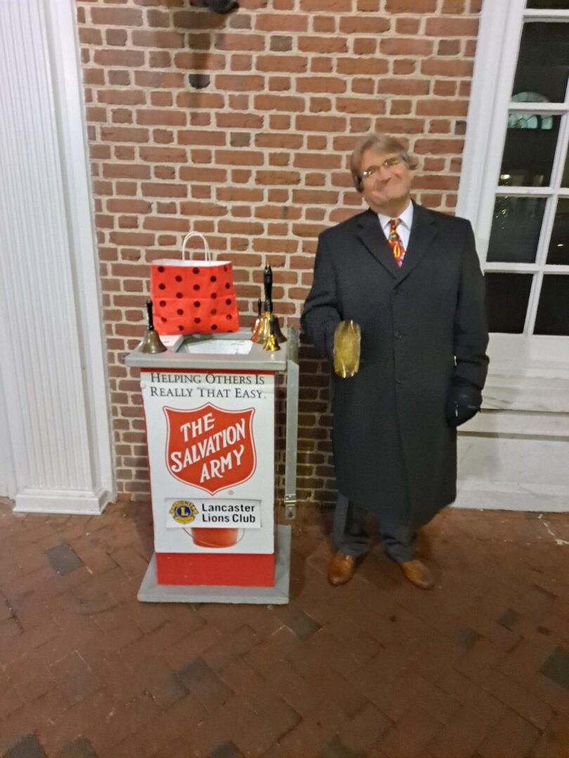 Man in black jacket standing next to the salvation army box