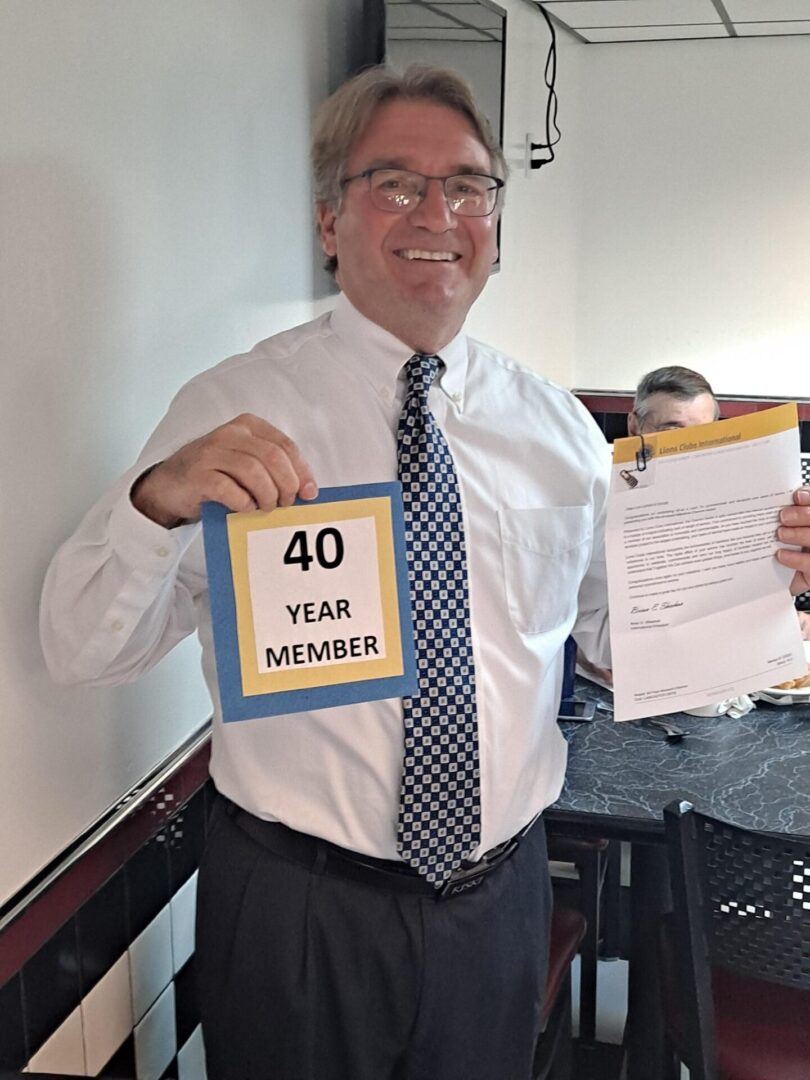 A Man Holding a Forty Year Member Board